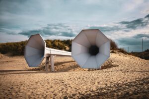 Spiaggia con sabbia che emette suoni melodiosi sotto i piedi, circondata da cartelli di protezione.