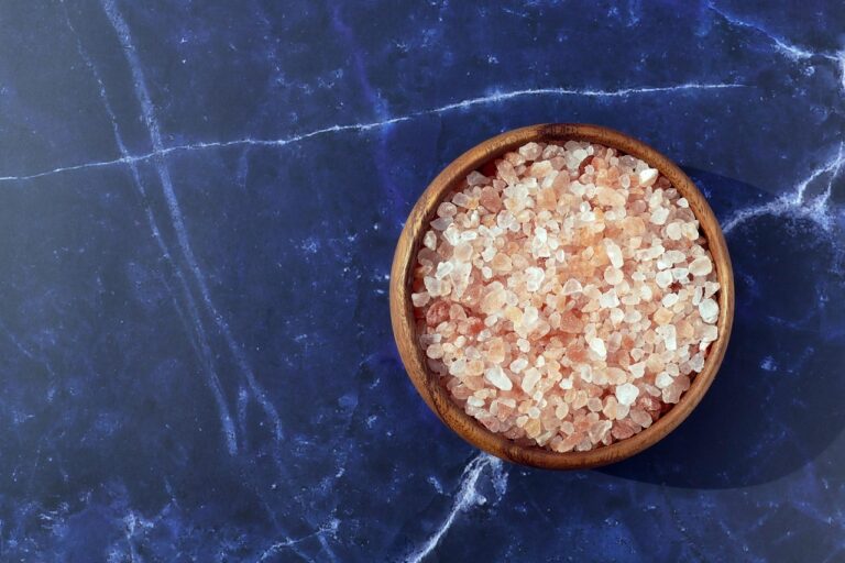 Sale rosa dell'Himalaya in un contenitore, con confronto visivo con sale marino sullo sfondo.